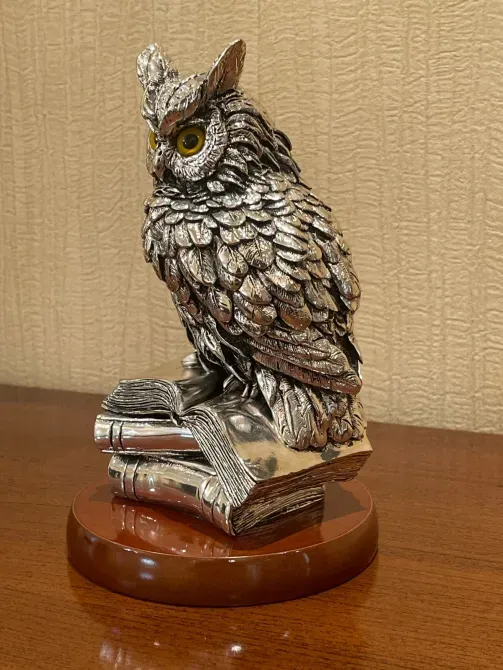 Изображение совы из металла, стоящей на книге