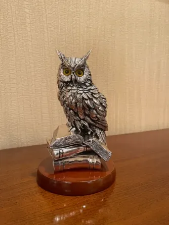 Статуэтка совы, расположенная на книжной подставке