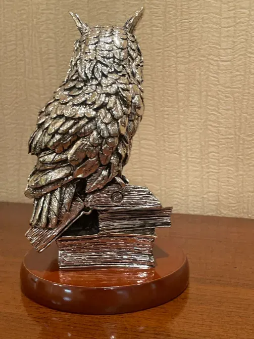 Статуэтка совы, расположенная на книжной подставке
