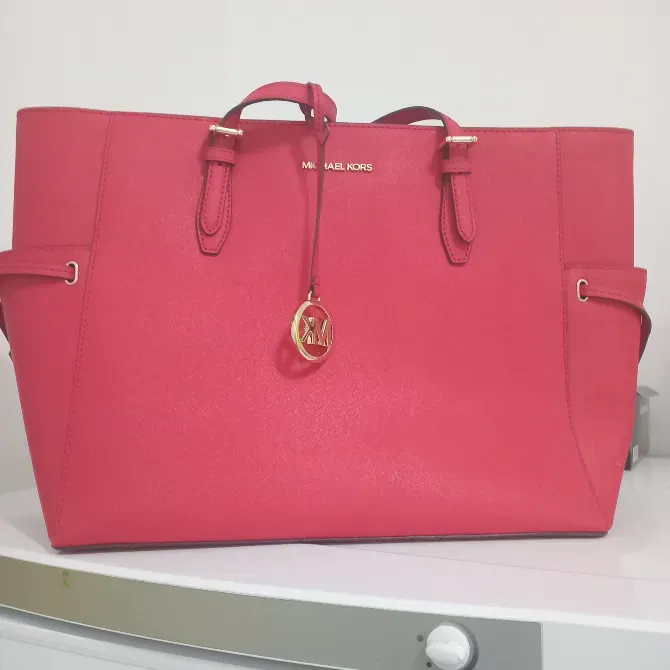 Красная сумка Michael Kors на белом фоне с золотистым логотипом