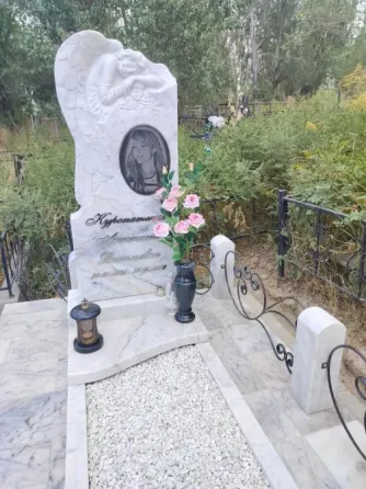 Могила с памятником и цветами на фоне зелени