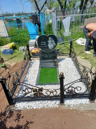 Могила с памятником и цветами на фоне зелени