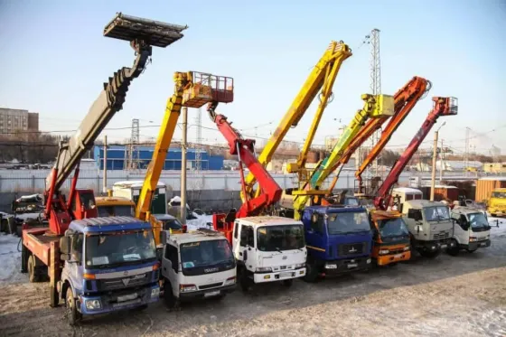 Группа автомобилей с подъемниками, стоящих в ряд на улице, зимний пейзаж с ясным небом