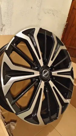 Колесо автомобиля с черными и хромированными спицами, вид спереди на картонной упаковке