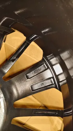 Колесо автомобиля с черными и хромированными спицами, вид спереди на картонной упаковке