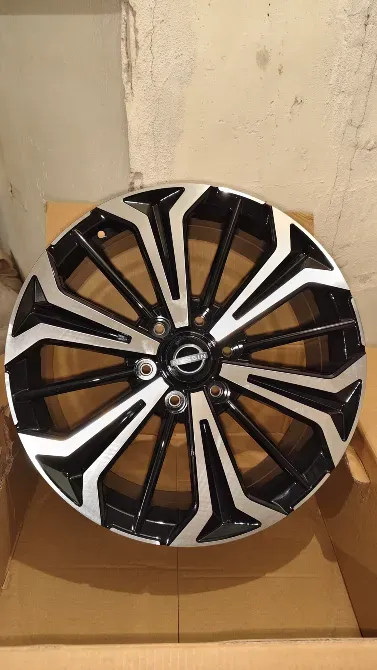 Колесо автомобиля с черными и хромированными спицами, вид спереди на картонной упаковке