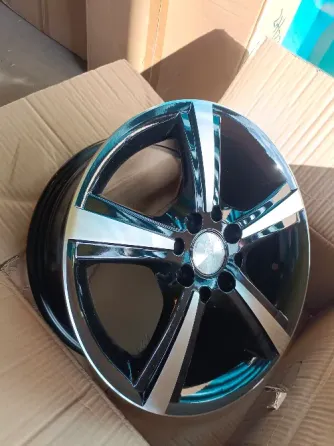 Диск колеса GW с черным и серебристым украшением на фоне синего контейнера