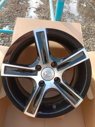 Диск колеса GW с черным и серебристым украшением на фоне синего контейнера