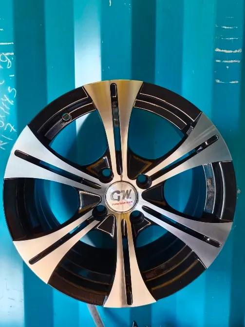 Диск колеса GW с черным и серебристым украшением на фоне синего контейнера