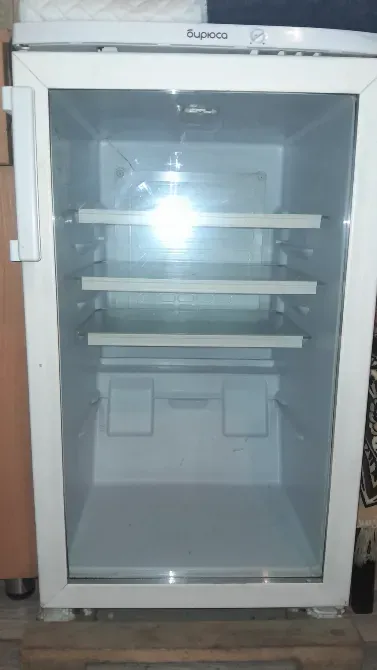 Пустой холодильник с прозрачными дверцами и металлическими полками