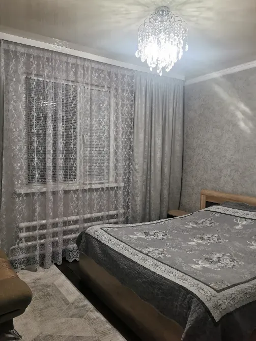 спальная комната с люстрой и занавесками