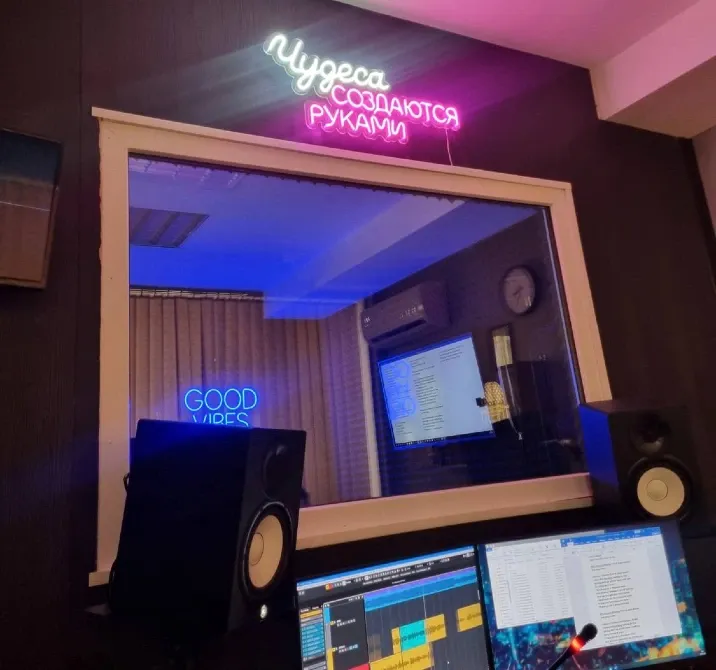 Интерьер звукозаписывающей студии с неоновыми вывесками и оборудованием