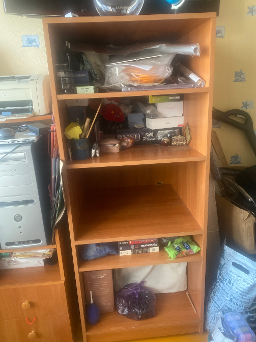 Түрлі заттармен кітап шкафы, жоғарғы сөре жүктелген, төменгі сөре бос