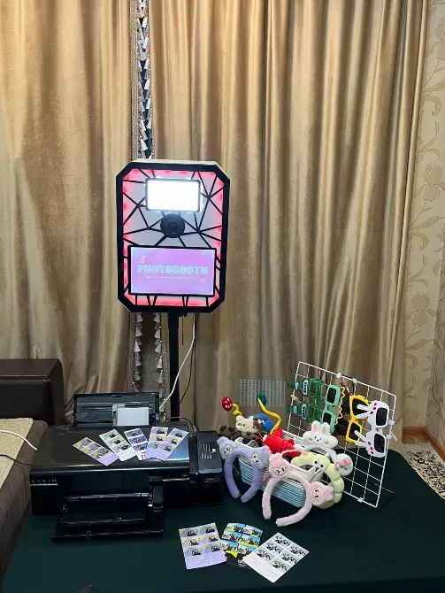 Аксессуарлармен, принтермен және үстелде басып шығарулармен фотобудка бөлмеде