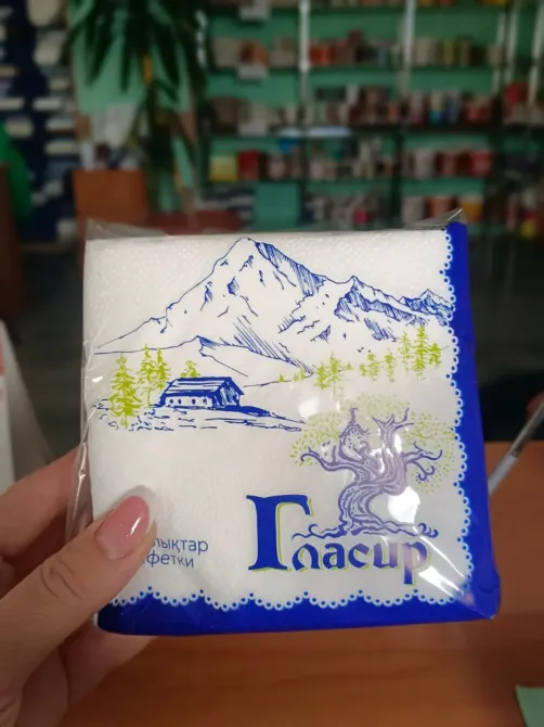 Тау мен ағаштың суреті бар ақ майлықтардың қаптамасы