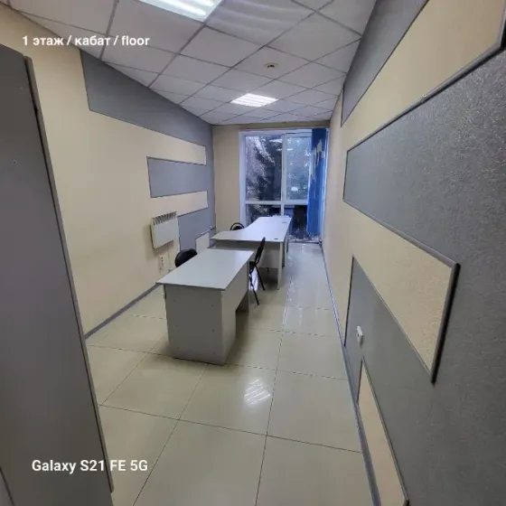 Жасыл шатырлы ғимарат және автотұрақтағы автокөліктер