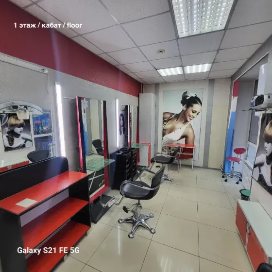 Жасыл шатырлы ғимарат және автотұрақтағы автокөліктер