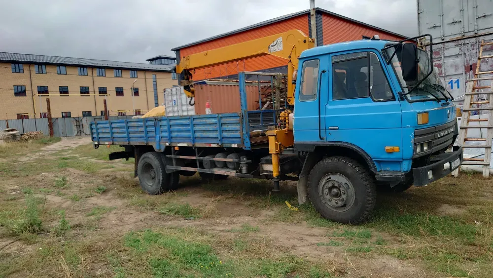 Ашық жерде тұрған кузовы мен краны бар көк жүк көлігі