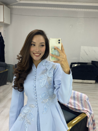 Изображение женщины с длинными волосами в светло-голубом наряде с вышивкой в зеркале