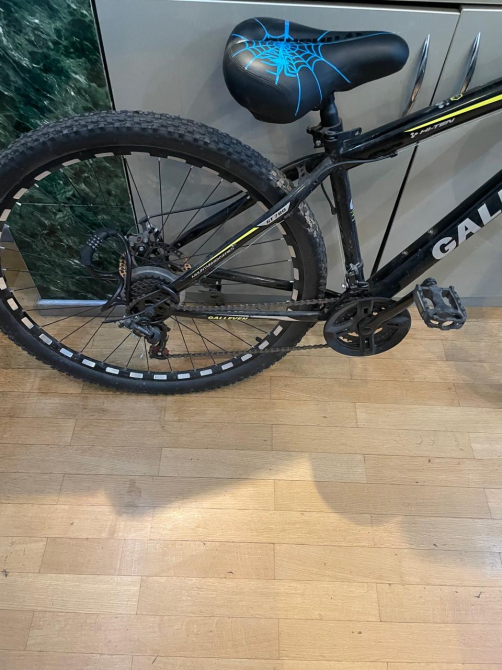 Вид на заднее колесо и трансмиссию велосипеда Calleven с черным каркасом и синим сиденьем