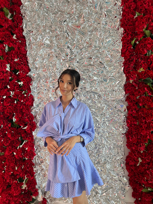 Девушка в полосатом платье позирует на фоне серебристого и красного декора