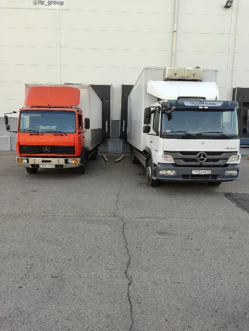 Екі Mercedes жүк көлігі, біреуі қызғылт сары, ал екіншісі ақ