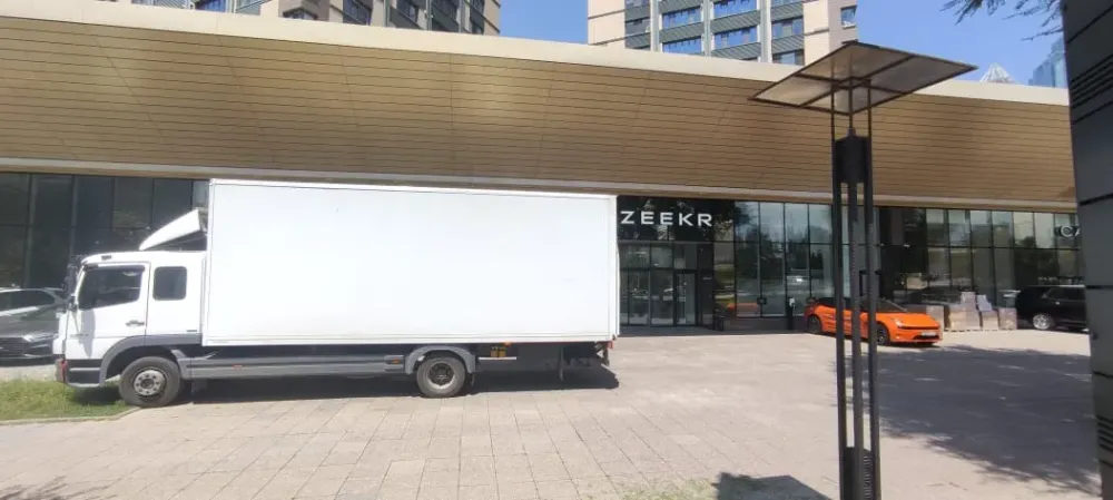 Ақ жүк көлігі Zeekr ғимаратының жанында