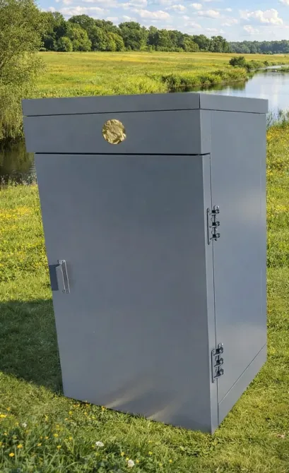 Закрытый почтовый ящик серого цвета на зеленом лугу