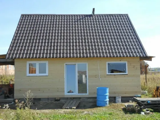 Крыша частного дома, покрытая металлочерепицей, на фоне голубого неба