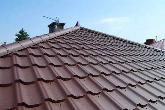 Крыша частного дома, покрытая металлочерепицей, на фоне голубого неба