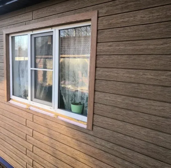 Стена дома, облицованная коричневыми кирпичами с белыми окнами