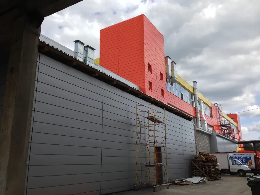 Сұр сайдинг және қызғылт сары жоғарғы бөлігі бар ғимарат қабырғасы