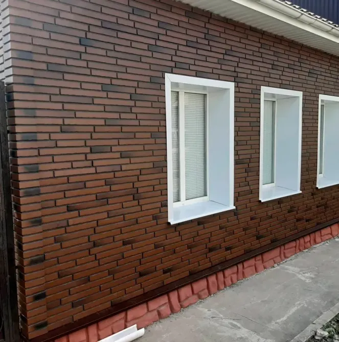 Коричневими кірпіштермен қапталған үй қабырғасы, ақ терезелермен
