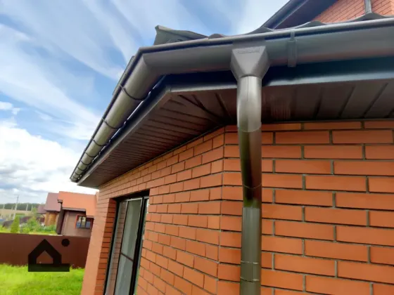 Крыша дома с водосточной системой и кирпичной отделкой