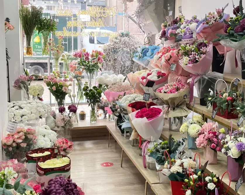 Букеттер мен гүлдік безендірулерге толы витринасы бар гүлдер дүкені
