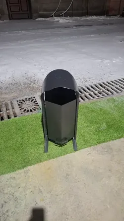 Металдық қоқыс жәшігі жасыл газонда