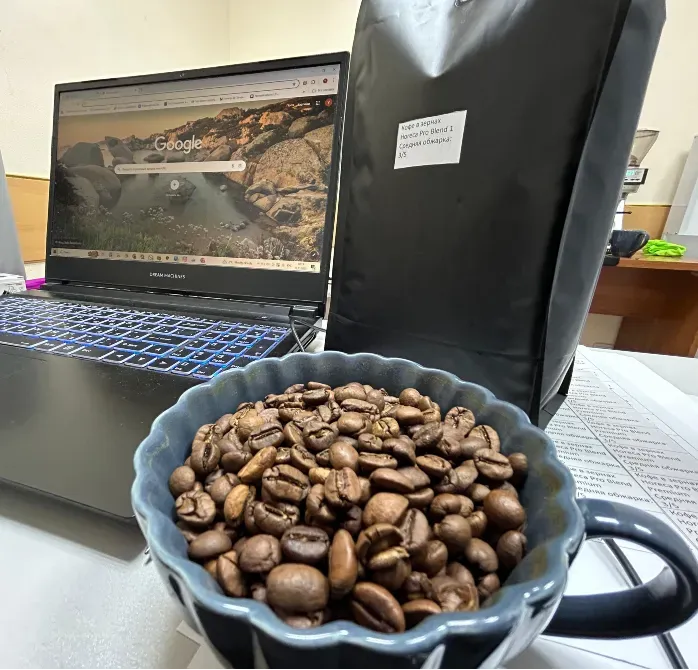 Ноутбукта Google, үстелде қара кофе пакеті және кофе бар кесе