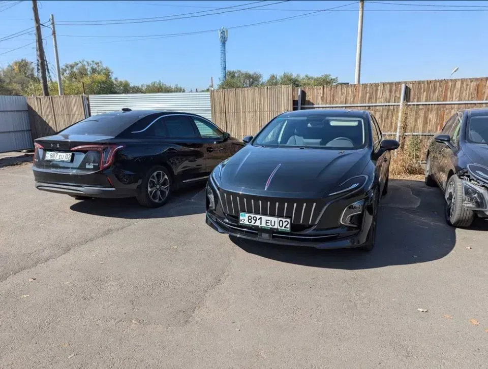 Екі қара автомобиль тұрақта, олардың бірі қызыл элементтерімен