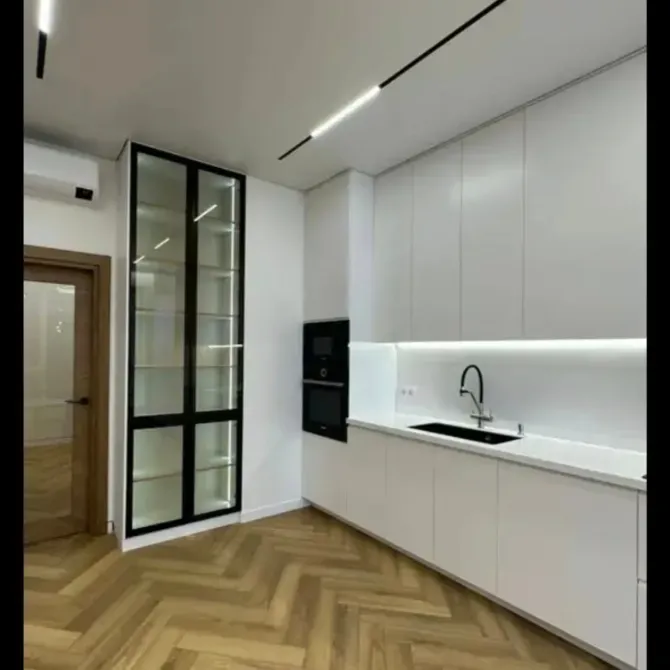 Современная кухня с белыми шкафами и деревянным полом