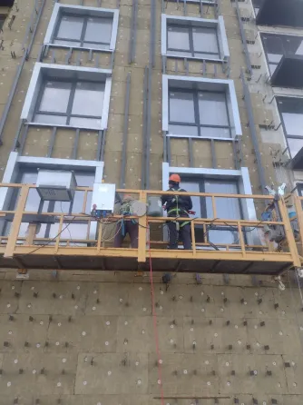 Рабочие на строительной площадке, занимающиеся отделкой фасада