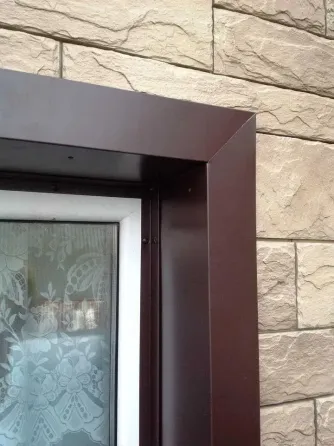 Уголок оконного профиля на фоне стены из камня