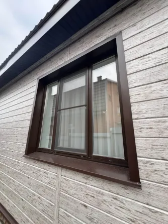 Уголок оконного профиля на фоне стены из камня