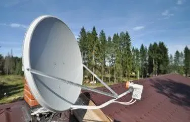 Спутниковая антенна на крыше дома в окружении природы