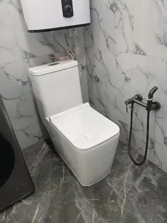 Унитаз на фоне мраморных стен в ванной