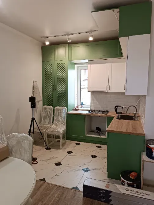 Кухня с зелеными шкафчиками и обеденными стульями