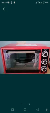 Қызыл электрлік духовой пеш мөлдір есігімен және басқару тұтқаларымен.