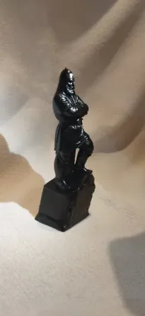 Статуэтка черного цвета, изображающая человека с перекрещенными руками