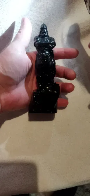 Қара түсті статуэтка, адамның қолында