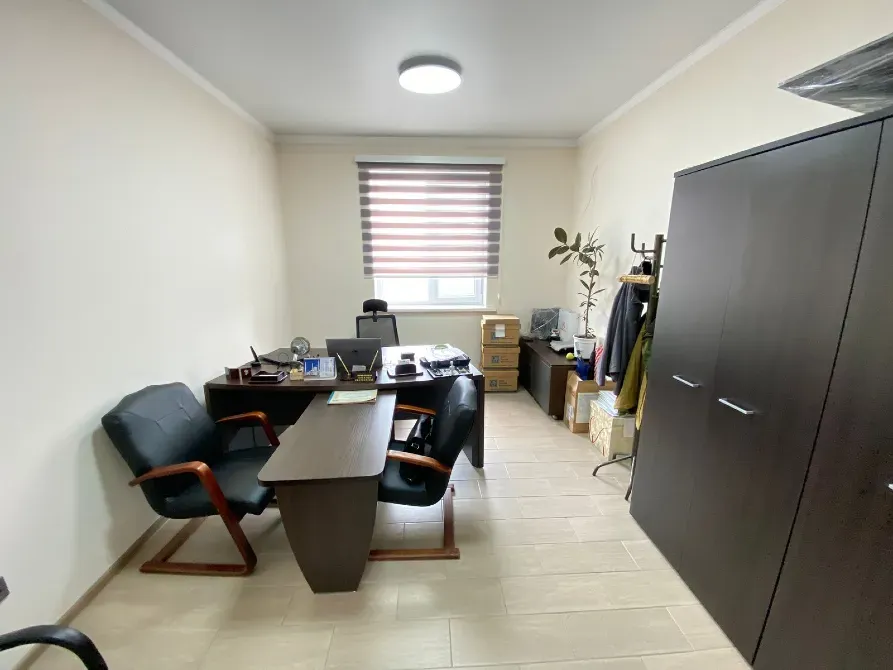 Офисное помещение с рабочими столами и стульями, оформленное в светлых тонах