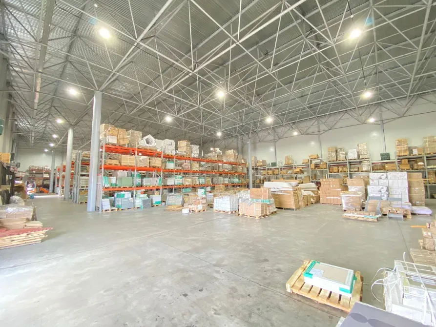 Просторный интерьер склада с высоким потолком и стеллажами, заполненными коробками